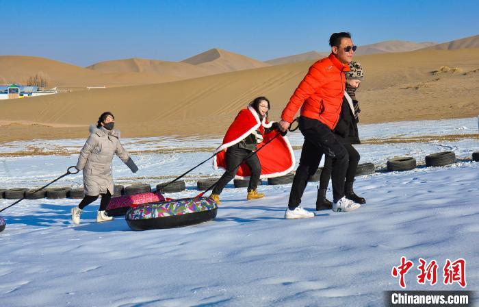 圖為游客和市民在鳴沙山下享受大漠冰雪帶來的歡樂?！⊥醣筱y 攝
