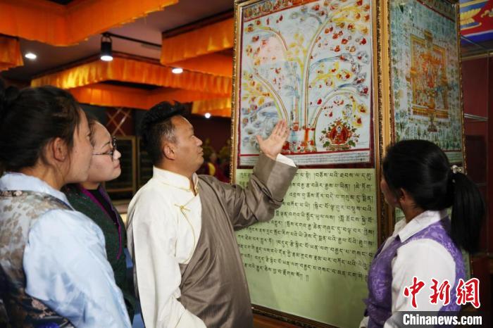 圖為普窮次仁(男)正在向?qū)W生講解“四部醫(yī)典”掛圖。(資料圖) 普窮次仁供圖